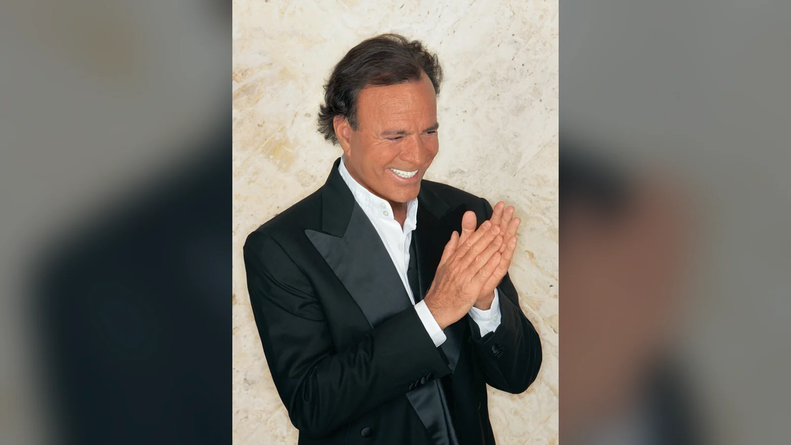 Julio Iglesias aplaudiendo con traje en 2005, para su carta astral y su astrocartografía